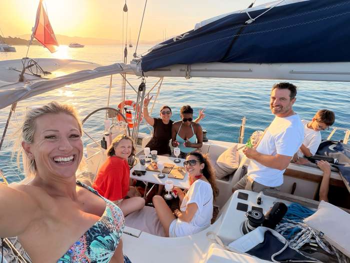 Groupe d'amis à bord d'un voilier au coucher du soleil